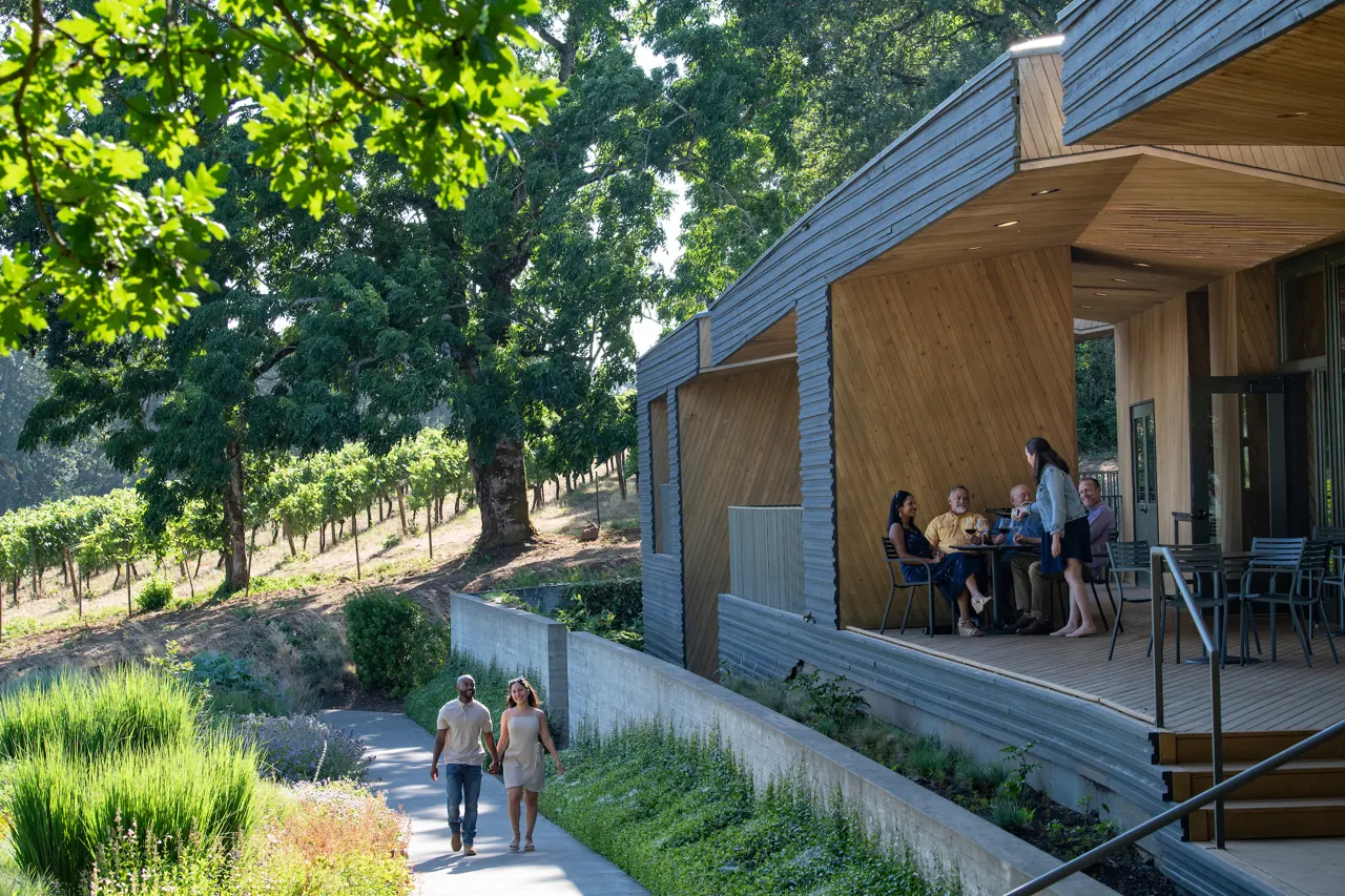 Guests on the covered terrace of the tasting room among oak trees and vines
