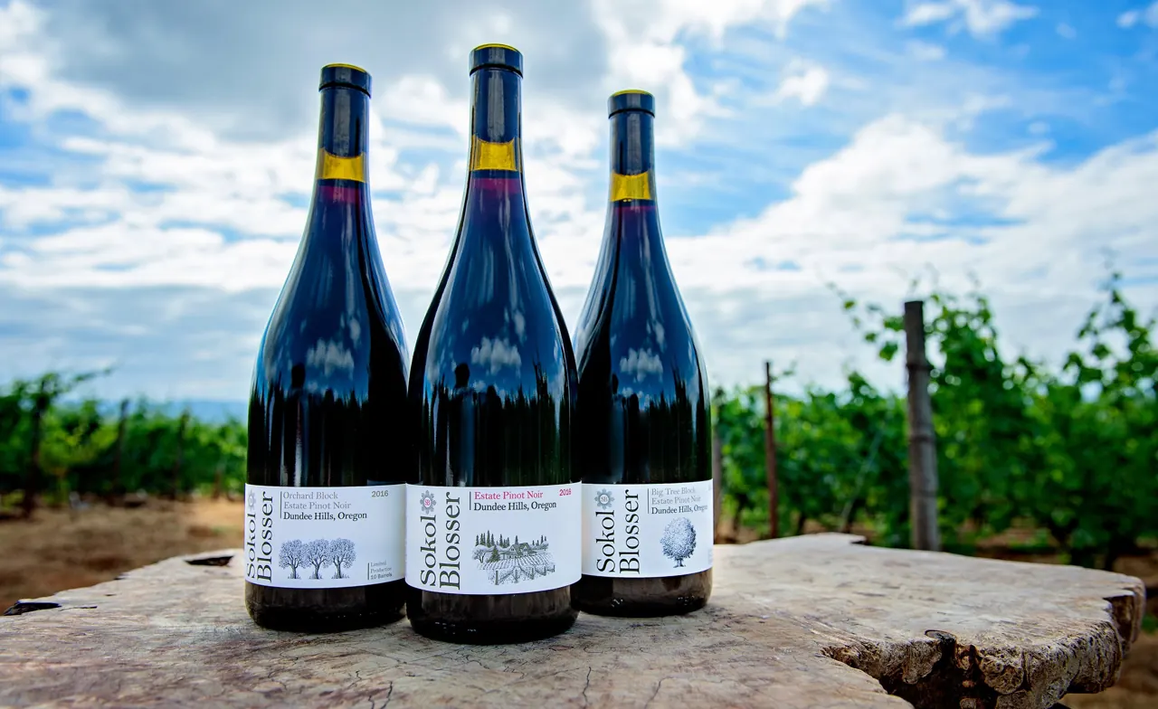 Three bottles of Sokol Blosser estate Pinot Noir in the vineyard